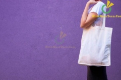 Blank white shopping canvas fabric cloth bag on female holding mockup and template isolated color background