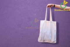 Blank white shopping canvas fabric cloth bag on female holding mockup and template isolated color background